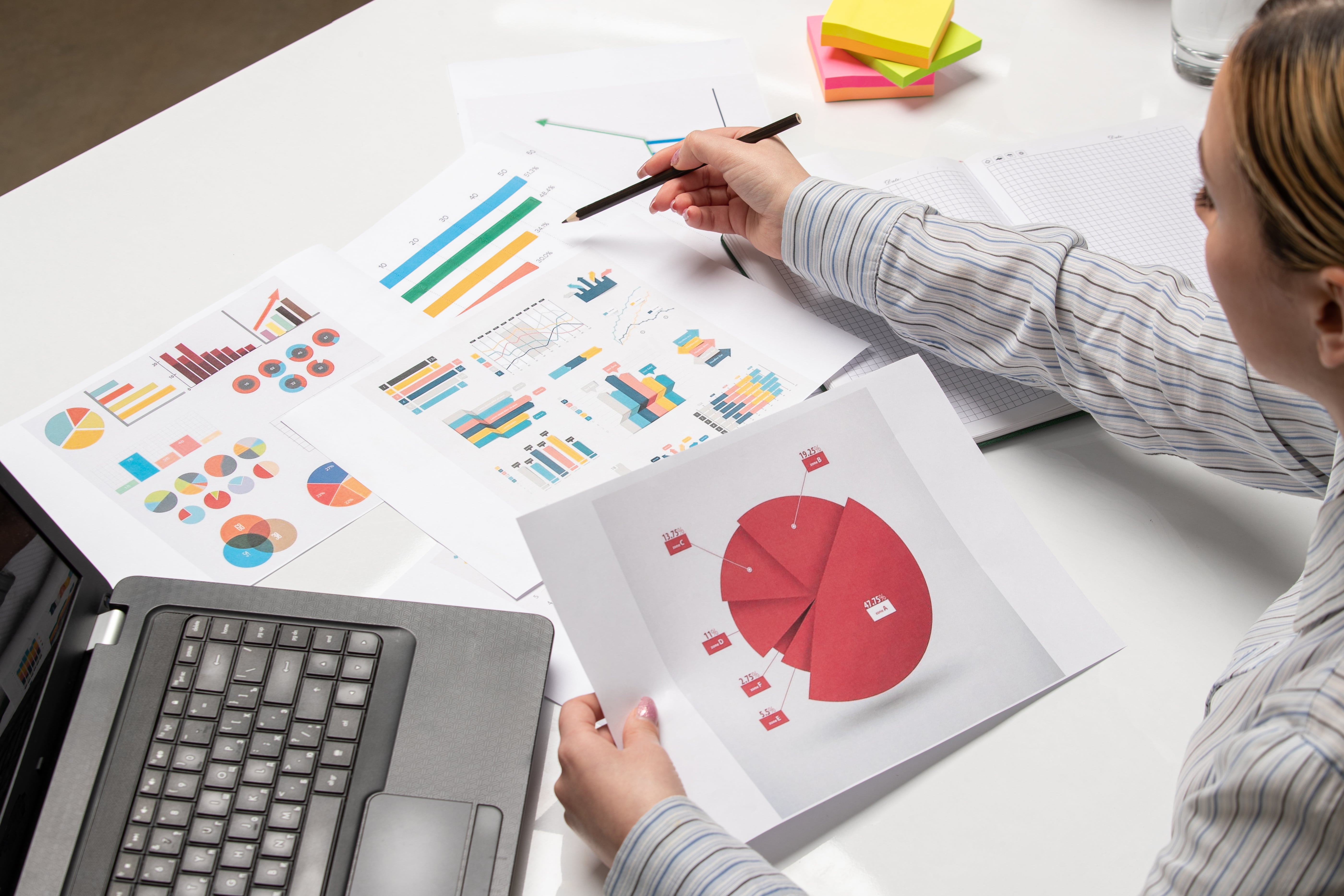 marketing-business-lady-striped-shirt-office-with-computer-pointing-graphs-charts-min